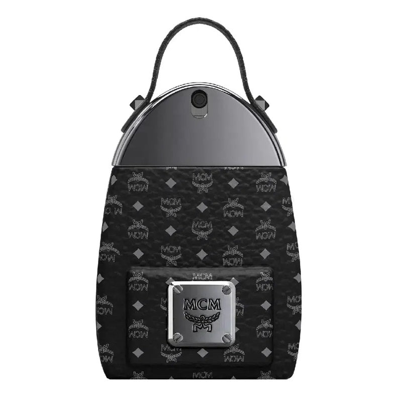 MCM mini backpack in black coated canvas with the signature monogram pattern, featuring a silver-tone metal top panel, black leather handle, and a silver-tone front metal plate with the MCM logo.