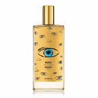 Memo Paris Marfa Eau de Parfum bottle with a gold cap and a gold body decorated with illustrated eyes, including a prominent blue and black eye in the center, on a white background.