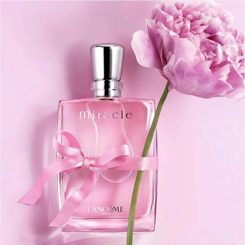 Lancome Miracle perfume bottle with a pink flower on a pink background