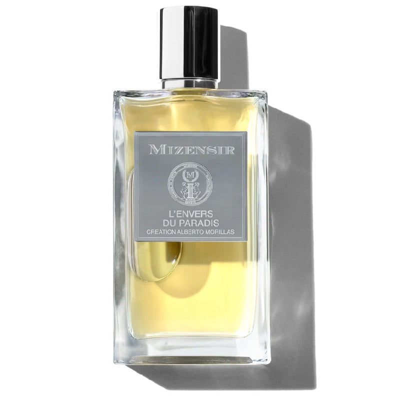 A rectangular glass bottle of L'Envers du Paradis perfume by Mizensir, with a clear yellow liquid visible inside and a black cap. The label features the brand name and the product name in elegant typography.