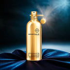 Gold perfume bottle on blue satin fabric with spray in action.