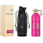 Pink perfume bottle with packaging and black drawstring bag on white background