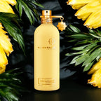 Montale perfume bottle with yellow flowers and green leaves on a dark background