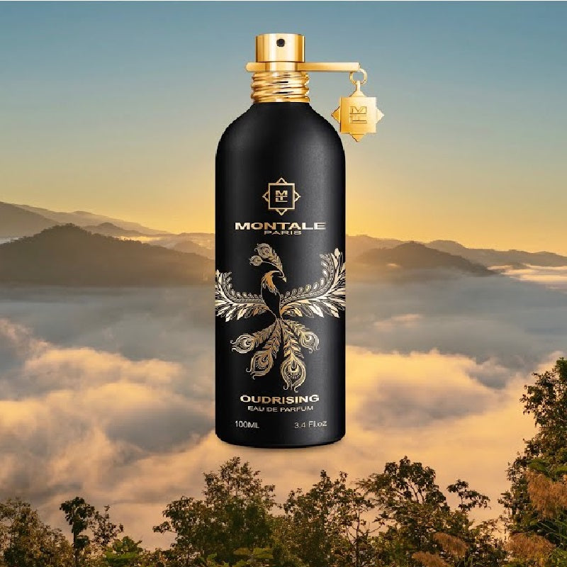 Perfume bottle with decorative design against a scenic background of mountains and mist.