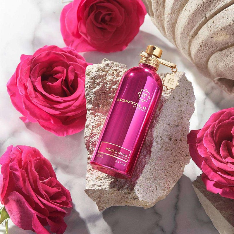 Montale Roses Musk perfume bottle surrounded by pink roses on a textured surface