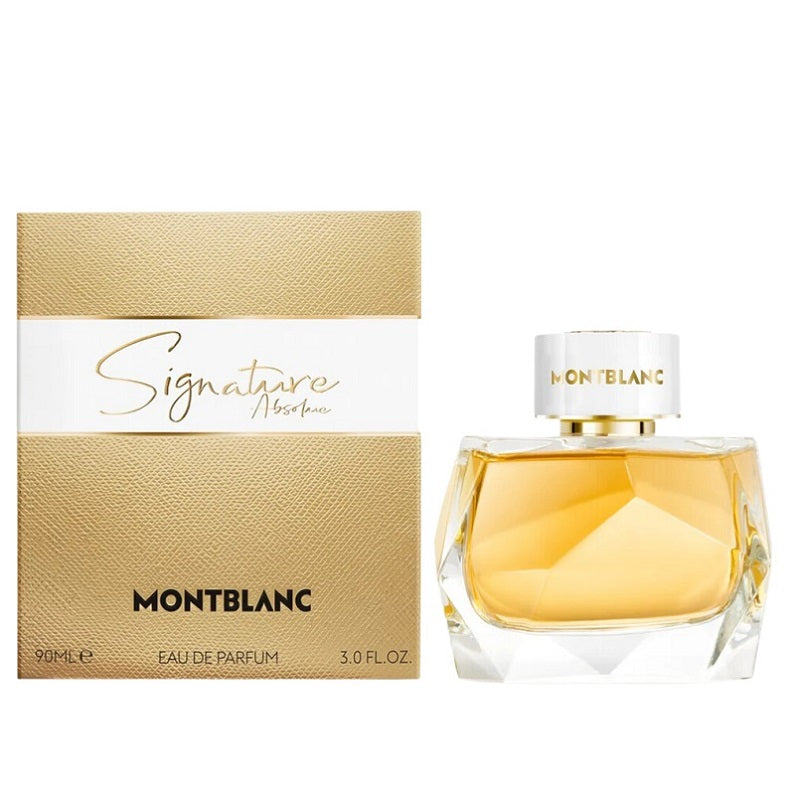 A bottle of Signature Absolue Eau De Parfum by Mont Blanc with its packaging box. The bottle is transparent with a gold-toned liquid and the packaging is gold with black text.