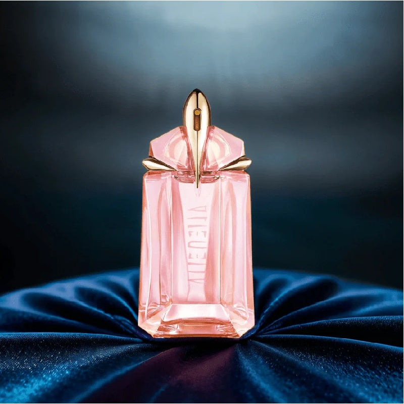 Pink perfume bottle with gold cap on a dark blue fabric background