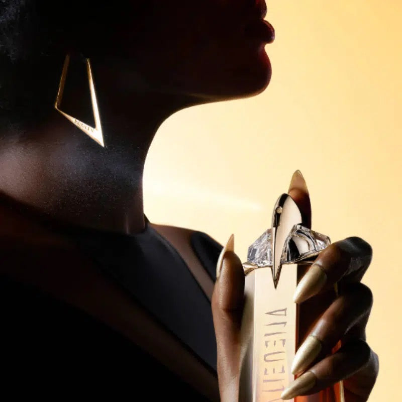 Silhouette of a person holding a perfume bottle with a diamond on a beige background