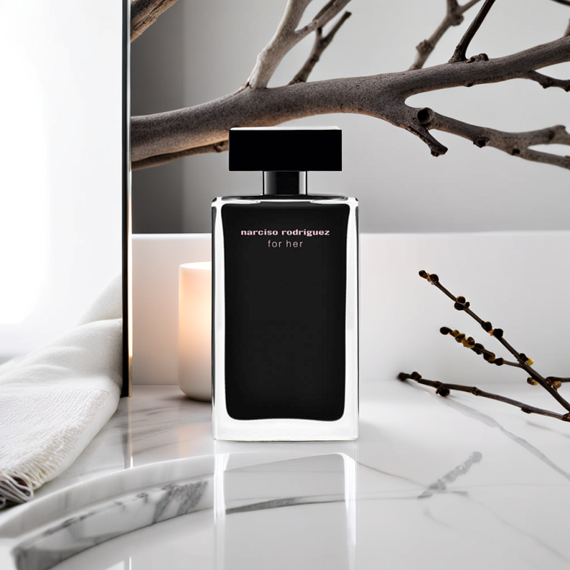 Perfume bottle on a marble surface with branches and candle in the background