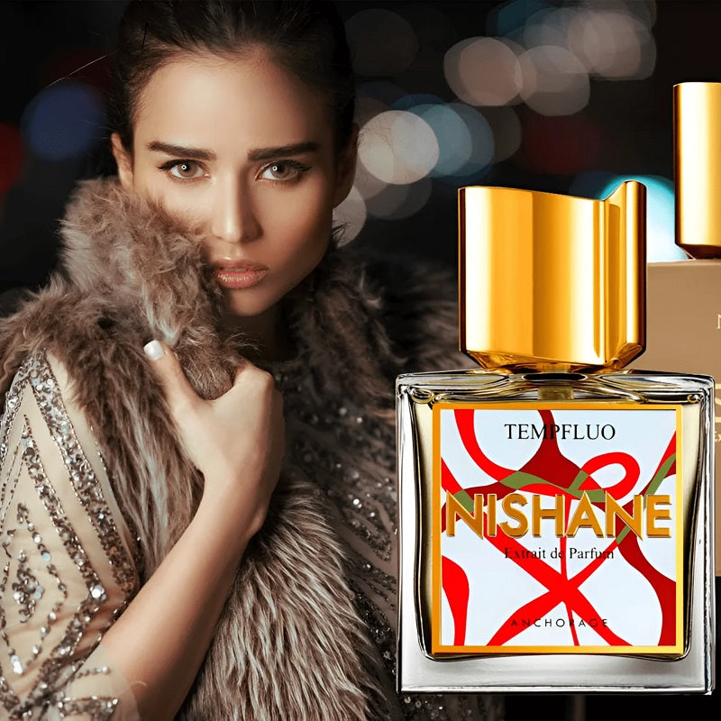 A woman in a fur-trimmed embellished dress poses beside a rectangular perfume bottle labeled NISHANE TEMPFLUO, with a large gold cap, on a dark blurred background.