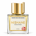 A square glass bottle of Nishane Extrait de Parfum by Petra, featuring a reflective gold cap, golden-yellow liquid, and a cream label with gold and black text and a red rose logo.