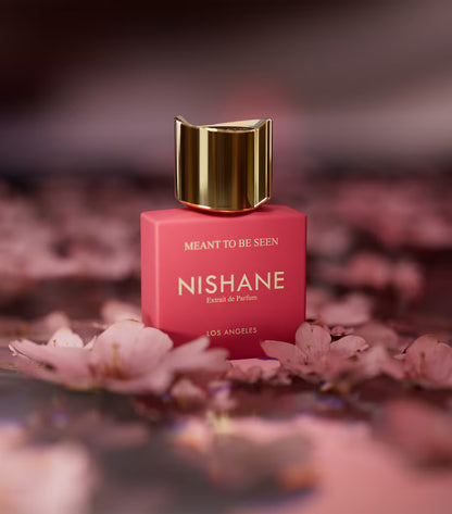 Nishane perfume bottle with gold cap on pink background