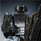Black and silver perfume bottle with a geometric design on a dark background