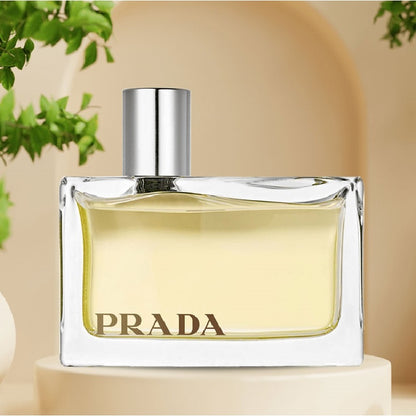 Prada perfume bottle on a beige background with greenery