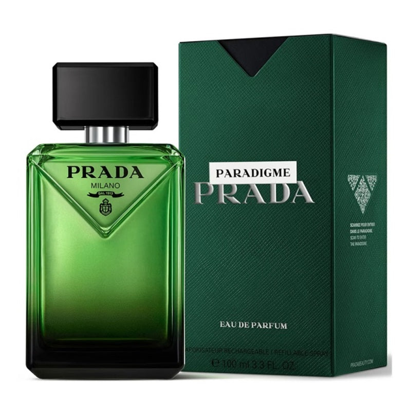 Prada Paradigme Milano Eau de Parfum bottle in green glass next to its textured dark green packaging box, on a white background.