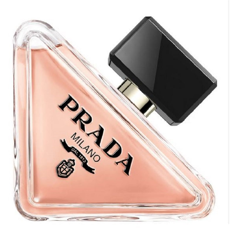 A triangular glass bottle of Prada Paradoxe eau de parfum with a black cap, showcasing the pinkish-tinted liquid inside.