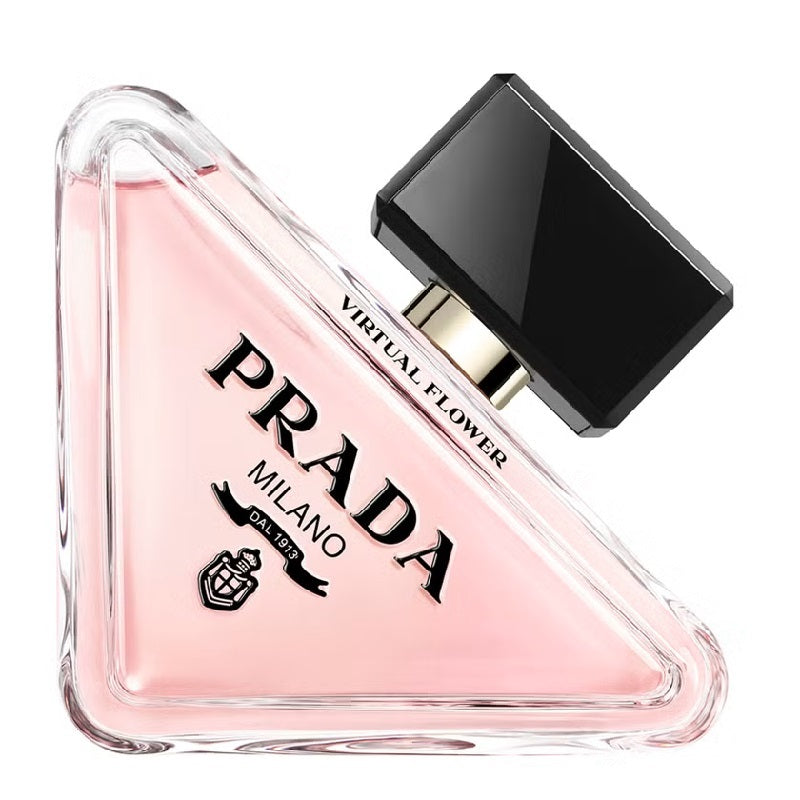 Prada Virtual Flower perfume bottle in a triangular clear glass design, filled with light pink liquid and featuring a glossy black cap, on a white background.
