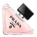 Prada Virtual Flower perfume bottle in a triangular clear glass design, filled with light pink liquid and featuring a glossy black cap, on a white background.