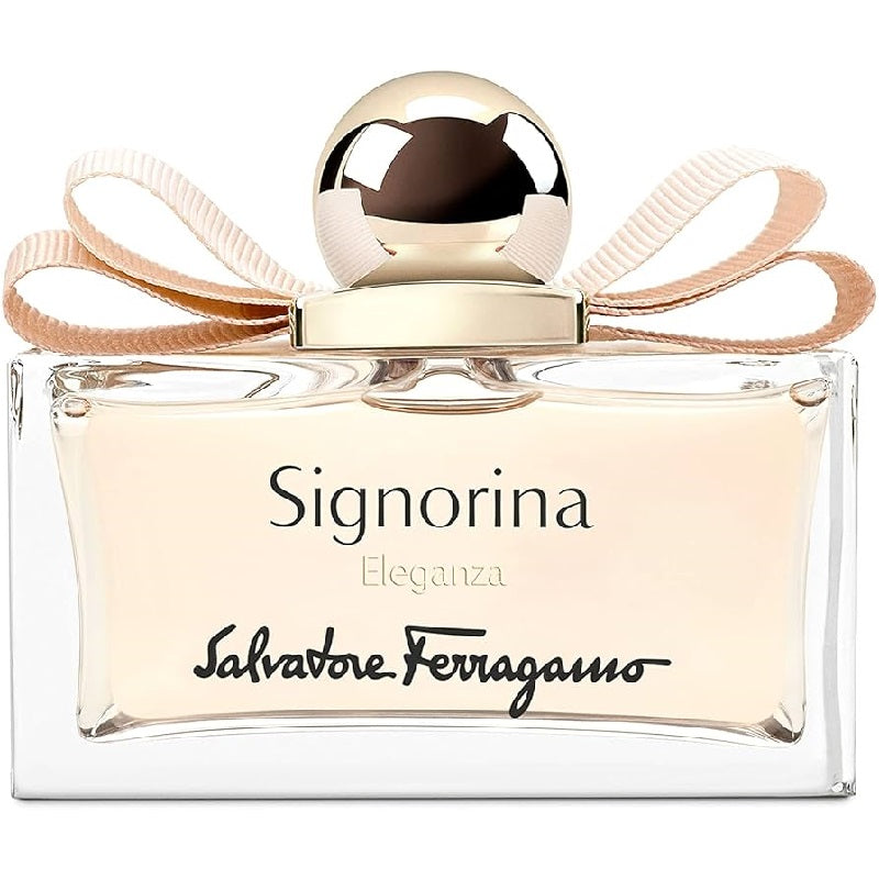 A bottle of Signorina Eleganza Eau de Parfum by Salvatore Ferragamo with a clear, elegant design and a beige ribbon around the top.