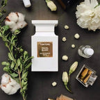 Tom FordSOLEIL BLANC perfume bottle surrounded by flowers and cotton on a dark surface