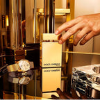 Dolce & Gabbana perfume bottle with a gold watch and bracelet on a reflective surface