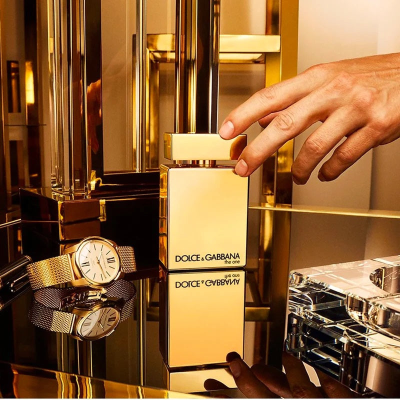 Dolce & Gabbana perfume bottle with a gold watch and bracelet on a reflective surface