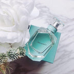 Tiffany & Co. perfume bottle on a matching box with white flowers in the background