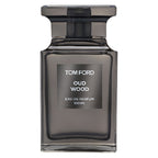 A 100ml bottle of Tom Ford Oud Wood Eau de Parfum with a dark tinted liquid visible through the clear glass bottle and a black cap.