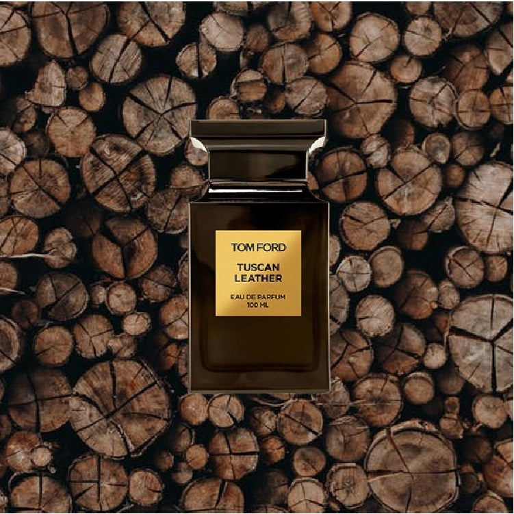 Tom Ford Tuscan Leather perfume bottle on a background of stacked wooden logs