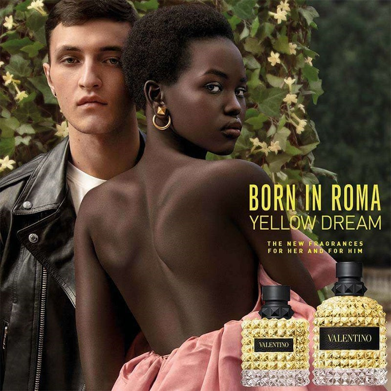 Two people standing together with two bottles of Valentina perfume labeled 'Born in Roma Yellow Dream' in the foreground.