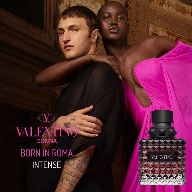 Two people embracing with a Valentino perfume bottle in the foreground.