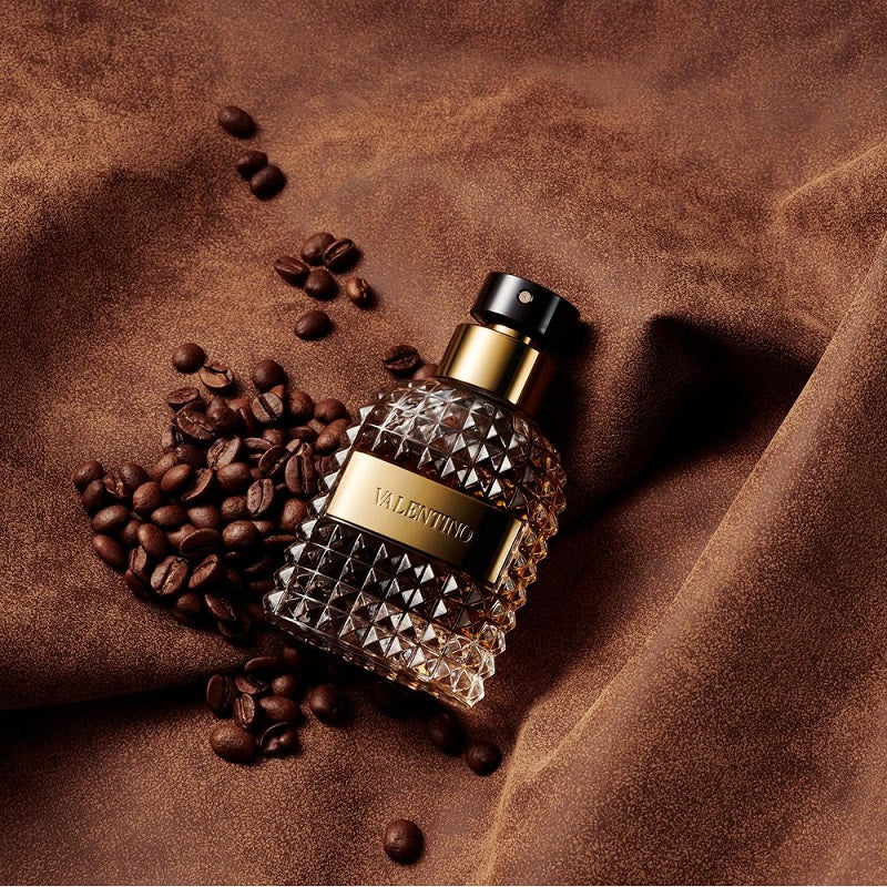 Perfume bottle with coffee beans on a brown fabric background