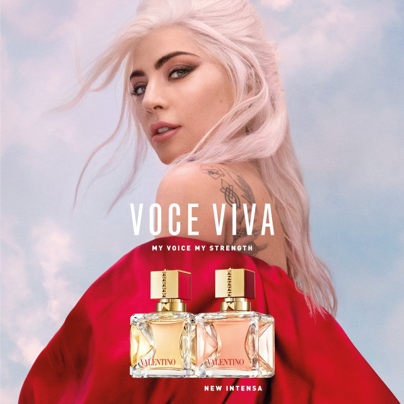 Advertisement for Valentino Voce Viva perfume with a woman in a red outfit against a sky background.