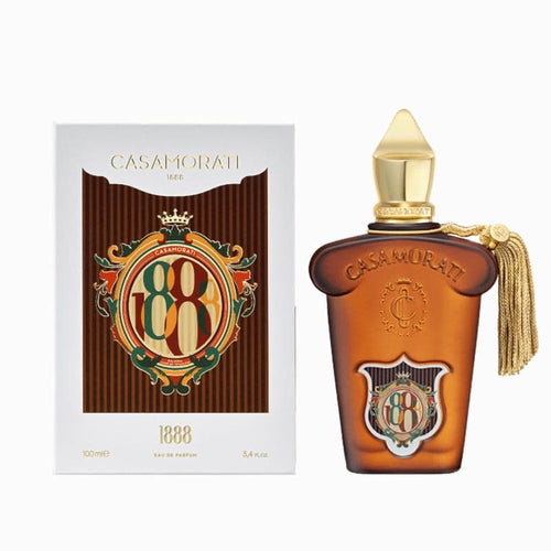 Casamora 1888 Eau de Parfum shown with its white and brown box packaging and the amber glass perfume bottle with a gold cap and tassel.