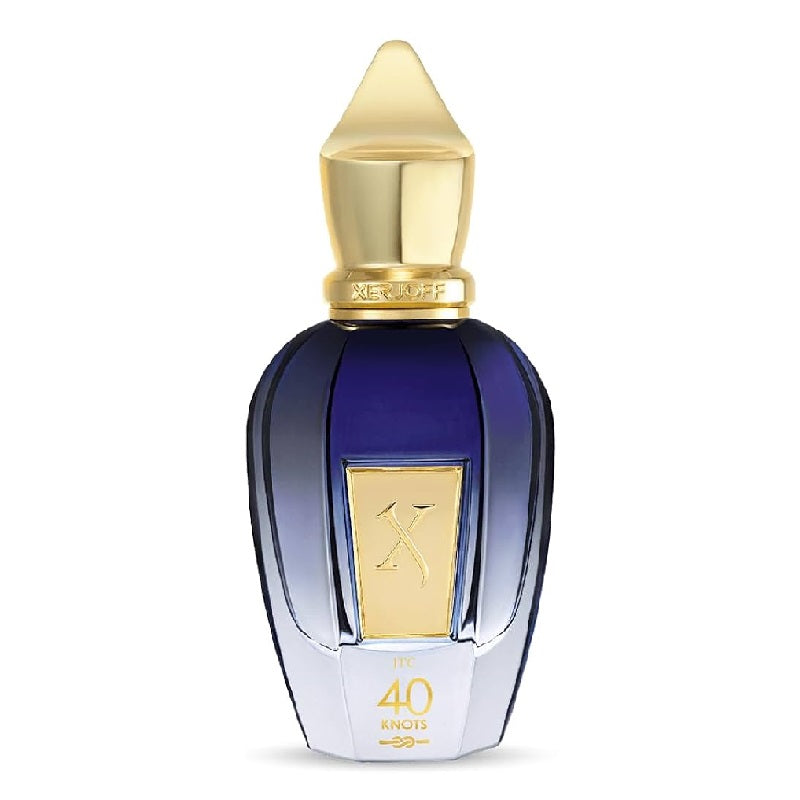 A luxury perfume bottle with a faceted dark blue glass body, a metallic gold cap, and a gold label featuring a stylized 'X' logo. The base of the bottle is white with gold lettering that reads '40 ENOIS'.