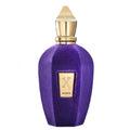 A purple velvet perfume bottle with a gold cap and a gold front label featuring an 'X' logo and the word 'ACCENTO'.