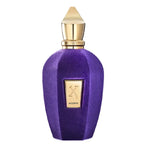A purple velvet perfume bottle with a gold cap and a gold front label featuring an 'X' logo and the word 'ACCENTO'.