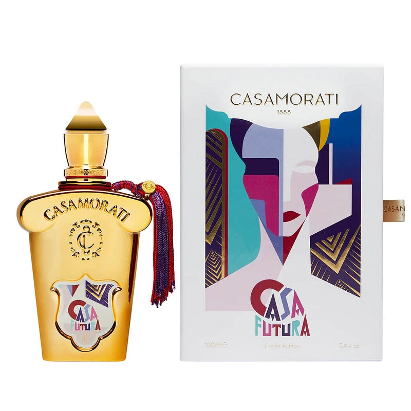 Casamorati Casa Futura perfume bottle in gold with a red tassel, shown next to its white packaging box featuring a colorful geometric face design.