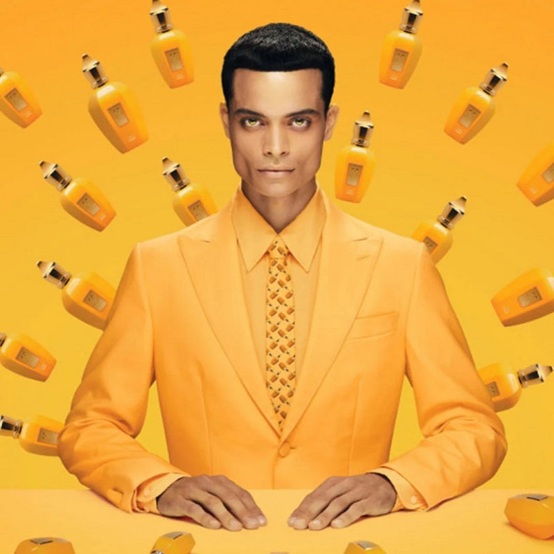 Man in an orange suit with matching tie and background featuring orange bottles.