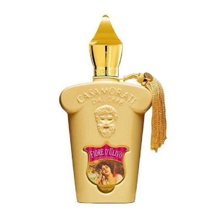 A gold-colored bottle of Casamorati Fiore D'ulivo eau de parfum with a decorative label and a tassel on the cap.