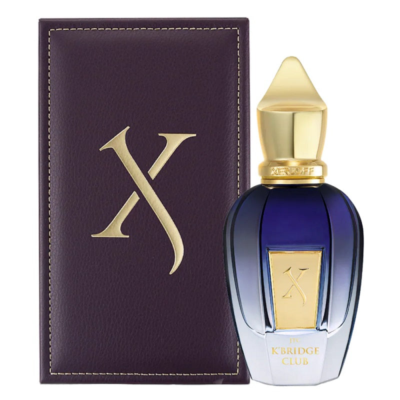Perfume bottle with gold cap and blue body next to a dark purple leather case with a gold 'X' on a white background