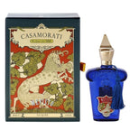 A product image featuring a blue perfume bottle with a white label, next to its packaging box with a unicorn illustration.