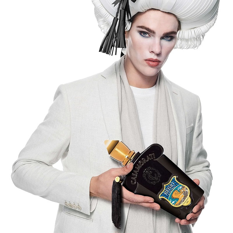 Person holding a black and gold bottle with a decorative label against a white background