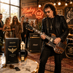 A rock star in a black sequined jacket and sunglasses plays an electric guitar in a lounge setting, while a perfume bottle and its box labeled XERUFF JONY IOMMI MONKEY SPECIAL are displayed on a marble table in the foreground.