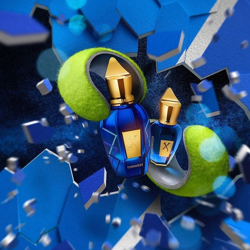 Two blue perfume bottles with gold caps on a blue geometric background