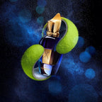Perfume bottle with gold cap and blue body on a green tennis ball against a dark background