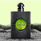 Yves Saint Laurent Black Opium perfume bottle on a textured surface with a light green background