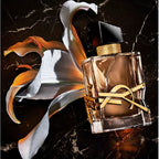 Perfume bottle with gold accents on a dark marble background with flowers