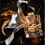 Perfume bottle with gold accents on a dark marble background with flowers