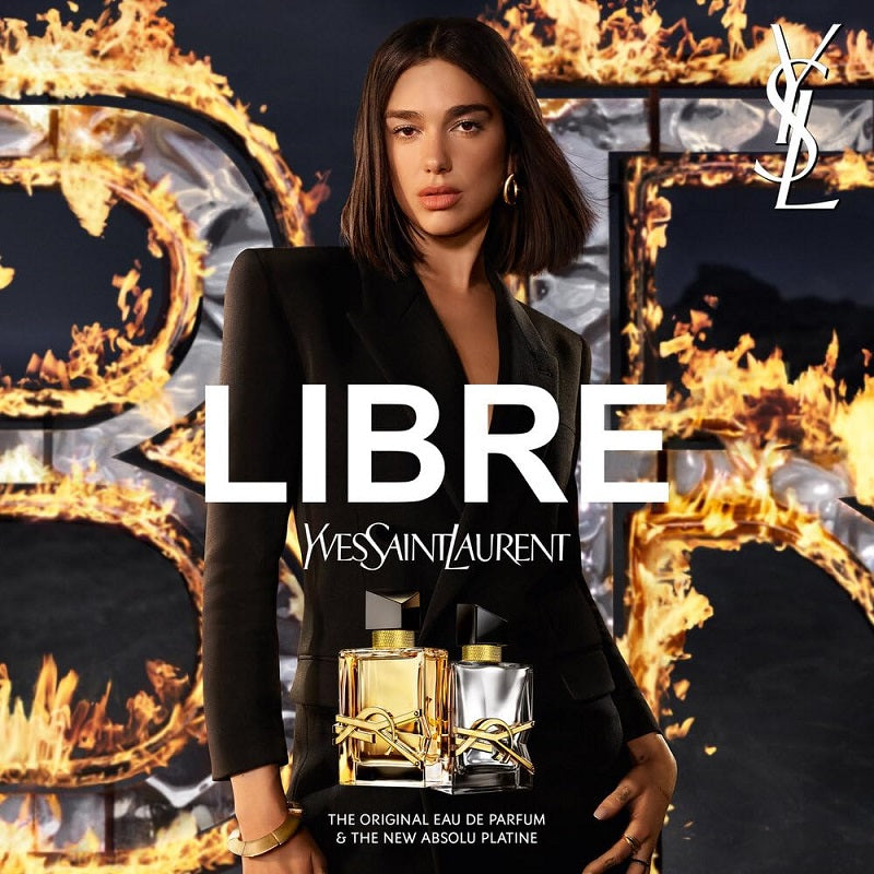 YSL Libre perfume advertisement with a model holding two perfume bottles against a fiery background.